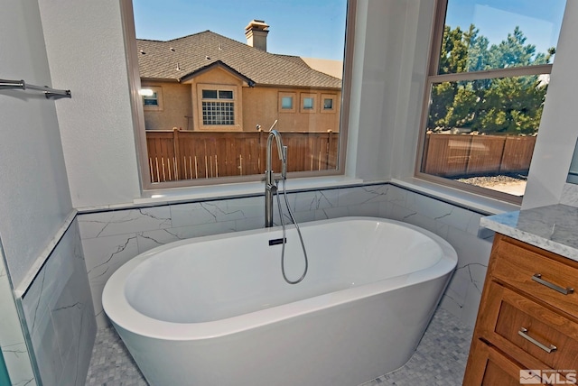 bathroom with vanity, a bath, and tile walls