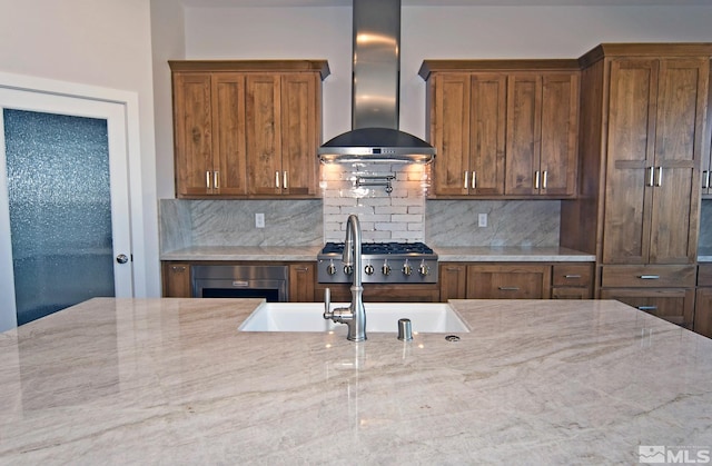 kitchen featuring sink, light stone counters, tasteful backsplash, beverage cooler, and wall chimney exhaust hood