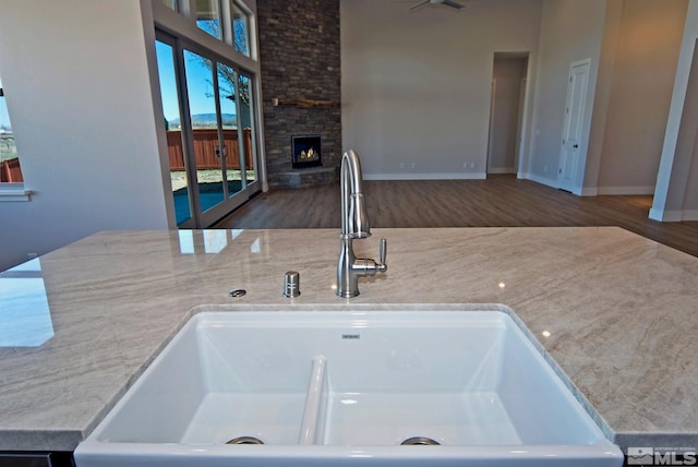 kitchen featuring light stone counters, a large fireplace, dark hardwood / wood-style flooring, and sink