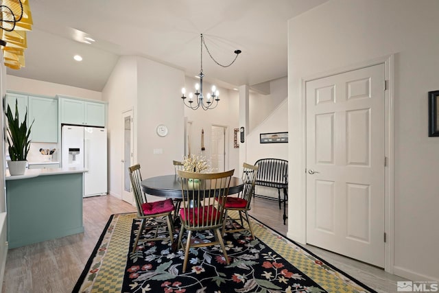 dining area featuring vaulted ceiling, light hardwood / wood-style flooring, and a notable chandelier