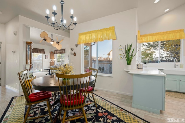 dining area with a notable chandelier, sink, and light hardwood / wood-style floors