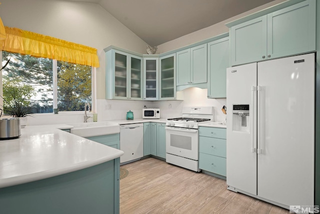 kitchen featuring light wood-type flooring, white appliances, vaulted ceiling, sink, and green cabinetry