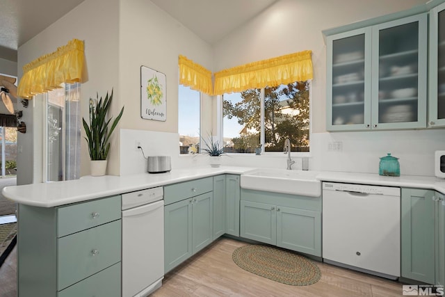 kitchen featuring sink, white dishwasher, light hardwood / wood-style floors, vaulted ceiling, and green cabinetry