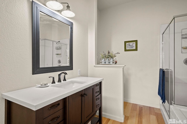 bathroom with hardwood / wood-style floors, vanity, and walk in shower