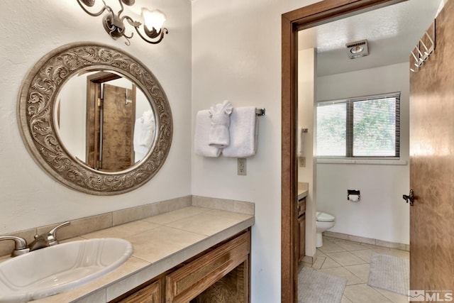 bathroom with tile patterned flooring, vanity, toilet, and a textured ceiling