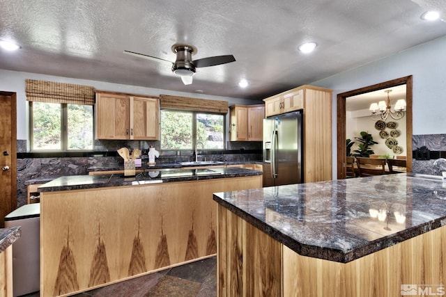 kitchen featuring a textured ceiling, decorative backsplash, stainless steel fridge with ice dispenser, and sink