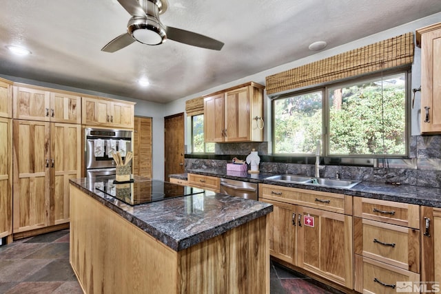 kitchen with appliances with stainless steel finishes, backsplash, ceiling fan, sink, and a center island