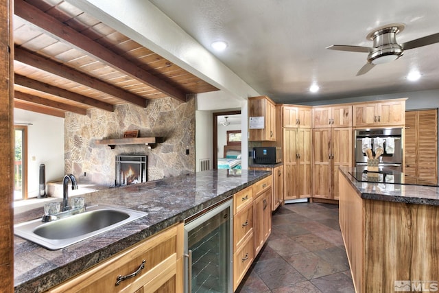 kitchen featuring a stone fireplace, sink, wine cooler, ceiling fan, and stainless steel double oven