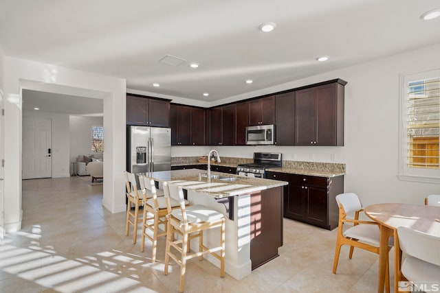 kitchen with dark brown cabinets, sink, appliances with stainless steel finishes, and light stone countertops