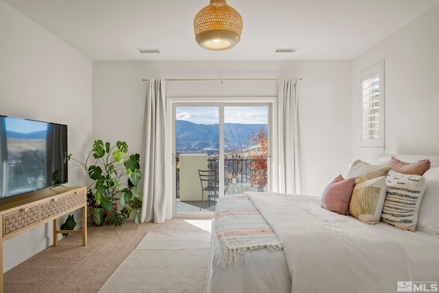 carpeted bedroom featuring access to exterior, a mountain view, and multiple windows