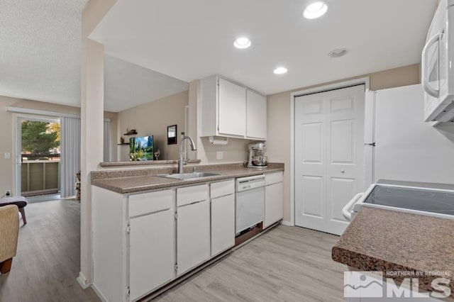 kitchen with white cabinets, light wood-type flooring, and white appliances