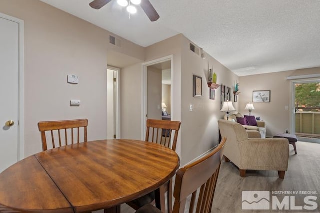 dining space featuring a textured ceiling, light hardwood / wood-style floors, and ceiling fan