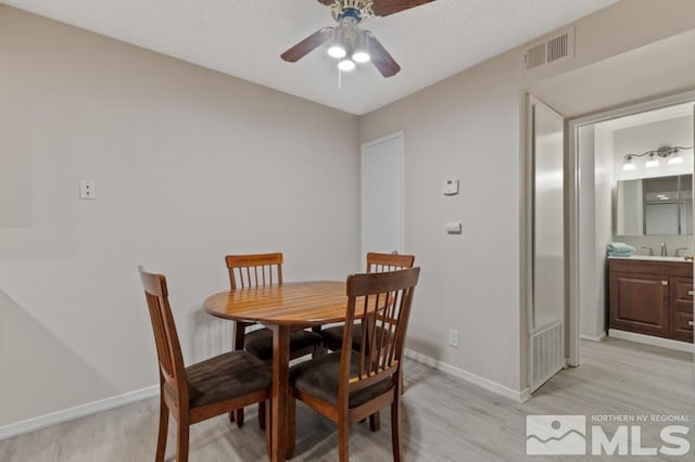 dining room with ceiling fan, light hardwood / wood-style floors, and sink