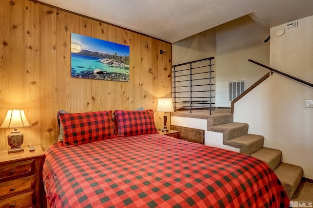 bedroom with carpet flooring, wood walls, and a textured ceiling