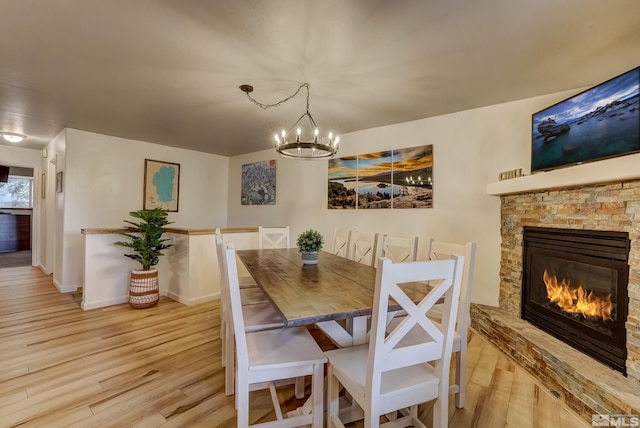 dining room with a fireplace, an inviting chandelier, and light hardwood / wood-style flooring