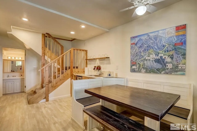 dining area featuring ceiling fan, sink, and light wood-type flooring