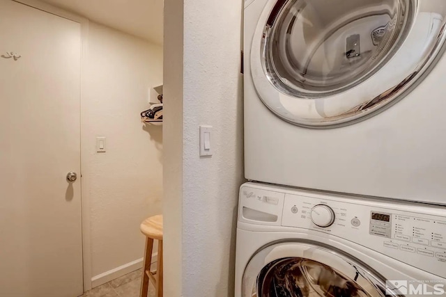 laundry area with stacked washer and dryer and light tile patterned flooring