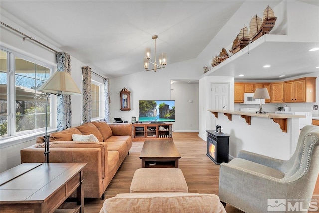 living room featuring light hardwood / wood-style flooring, lofted ceiling, and an inviting chandelier