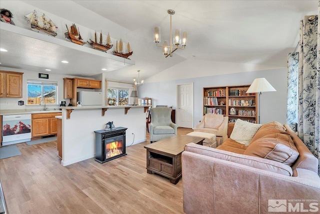 living room featuring sink, light hardwood / wood-style floors, lofted ceiling, and an inviting chandelier