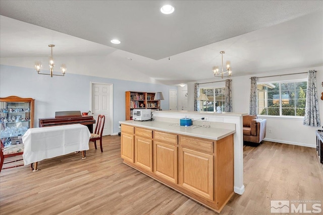 kitchen featuring decorative light fixtures, a chandelier, vaulted ceiling, and light wood-type flooring