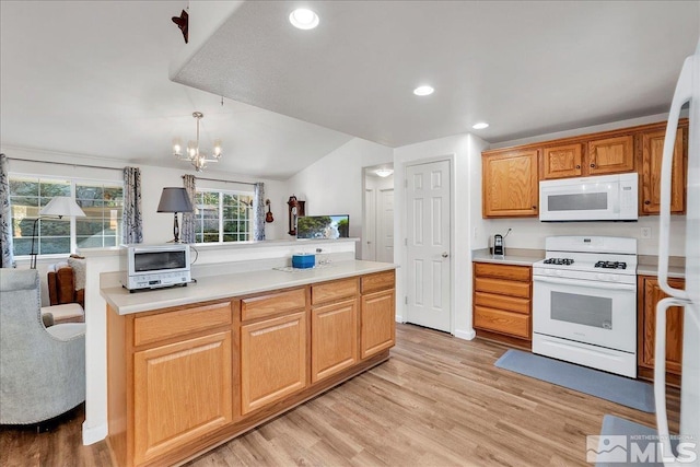 kitchen with white appliances, vaulted ceiling, pendant lighting, light hardwood / wood-style flooring, and a chandelier