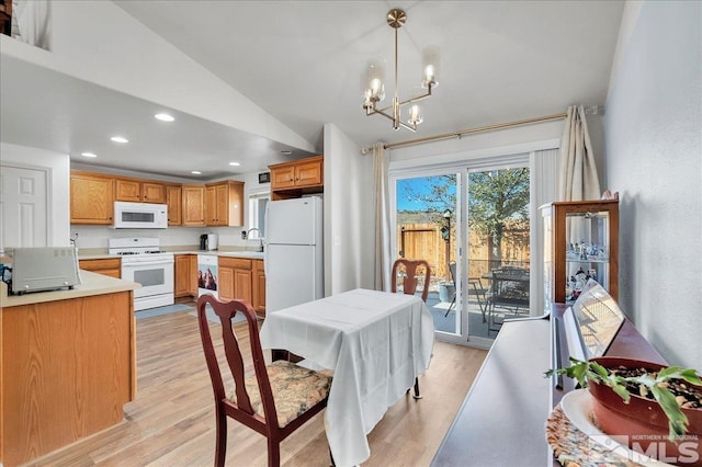 kitchen with sink, hanging light fixtures, vaulted ceiling, white appliances, and light wood-type flooring