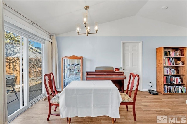 dining area with a notable chandelier, lofted ceiling, and light wood-type flooring