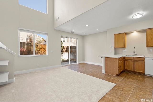 kitchen featuring kitchen peninsula, dishwasher, sink, and light carpet