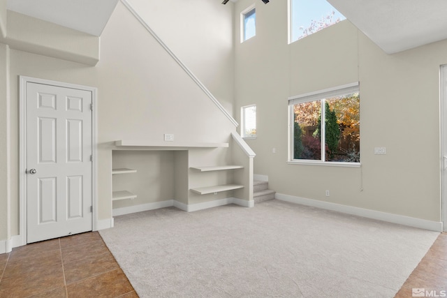 unfurnished living room with carpet floors and a high ceiling