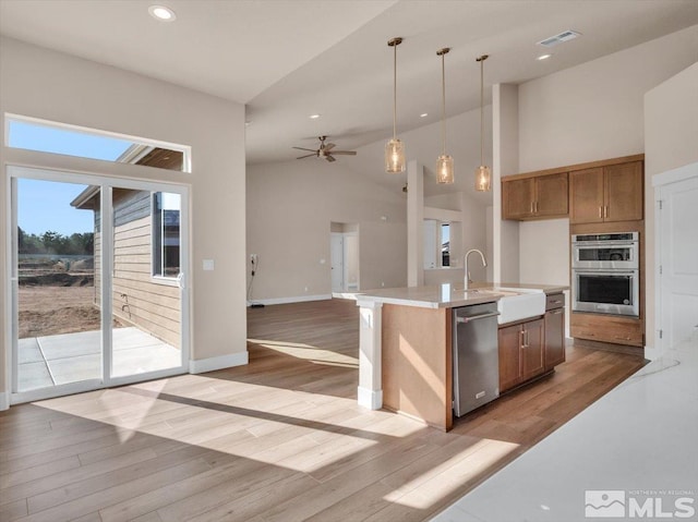 kitchen featuring hanging light fixtures, a kitchen island with sink, sink, and light hardwood / wood-style floors