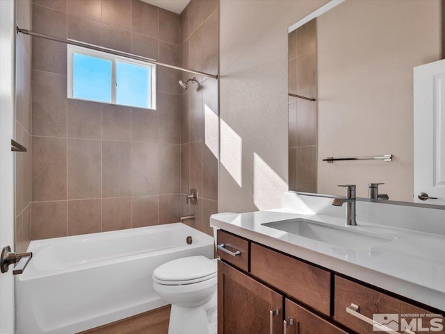 full bathroom with hardwood / wood-style flooring, tiled shower / bath combo, toilet, and vanity