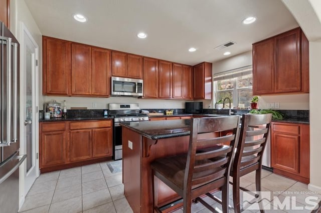 kitchen featuring dark stone counters, light tile patterned floors, stainless steel appliances, and a kitchen island