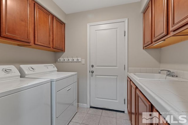 laundry room with cabinets, separate washer and dryer, sink, and light tile patterned floors