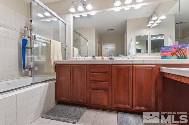 bathroom with tile patterned flooring, vanity, and bath / shower combo with glass door