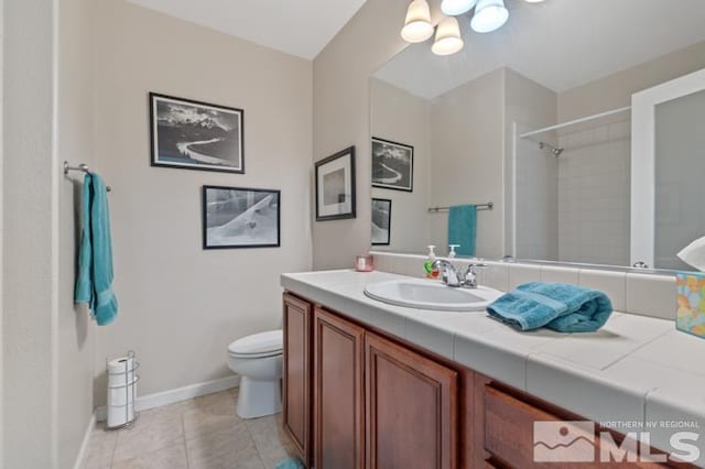 bathroom featuring toilet, a tile shower, vanity, and tile patterned floors