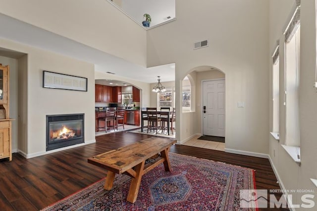 living room with a towering ceiling, an inviting chandelier, and light hardwood / wood-style flooring