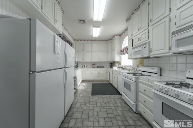 kitchen with white cabinetry, white appliances, sink, and tasteful backsplash