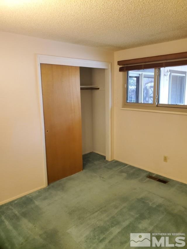 unfurnished bedroom featuring carpet, a textured ceiling, and a closet