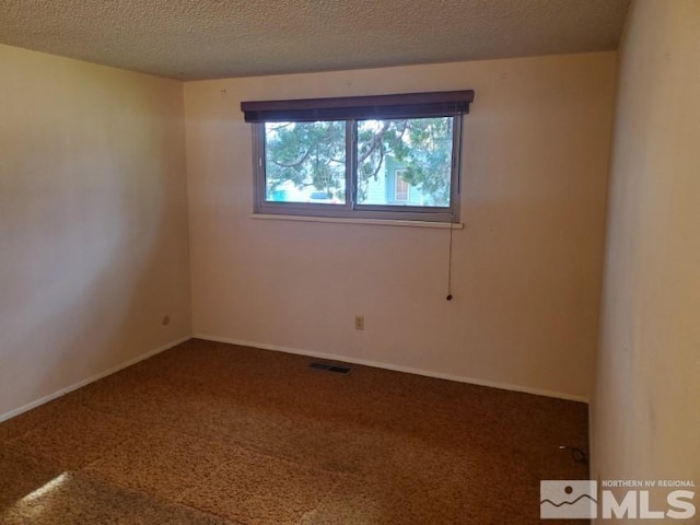 carpeted spare room featuring a textured ceiling