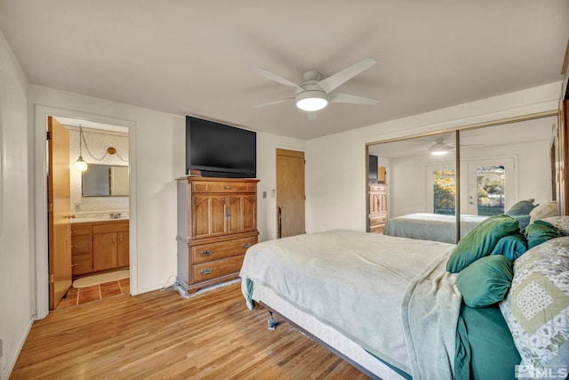 bedroom featuring ensuite bath, ceiling fan, sink, and light wood-type flooring