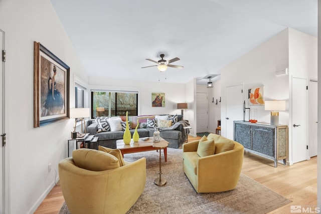 living room with ceiling fan, light hardwood / wood-style flooring, and vaulted ceiling