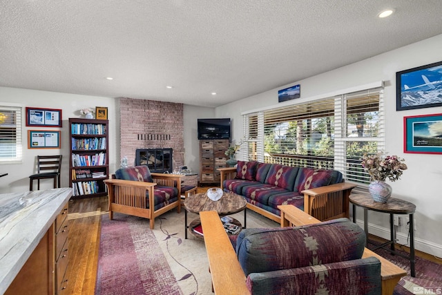 living room with a fireplace, a textured ceiling, and dark hardwood / wood-style floors