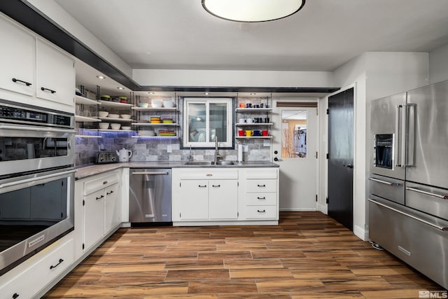 kitchen with appliances with stainless steel finishes, sink, white cabinetry, and hardwood / wood-style floors