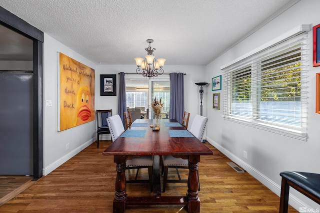 dining room featuring a chandelier, a textured ceiling, and dark hardwood / wood-style flooring