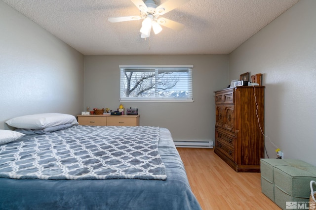 bedroom with a textured ceiling, light hardwood / wood-style floors, a baseboard radiator, and ceiling fan