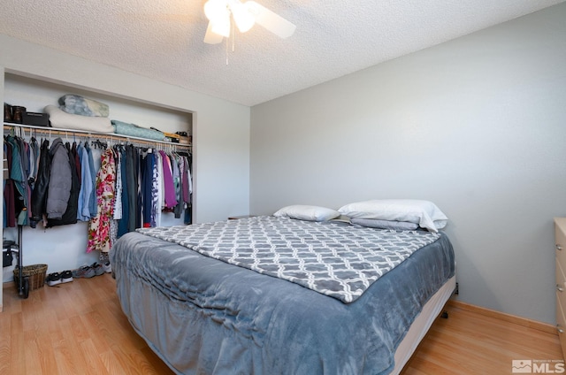 bedroom featuring ceiling fan, a closet, a textured ceiling, and light wood-type flooring