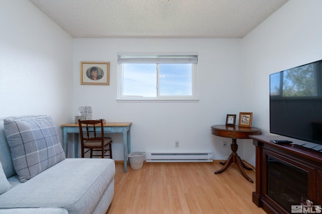 living area featuring a textured ceiling, light wood-type flooring, and a baseboard heating unit