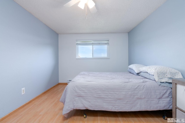 bedroom with ceiling fan, wood-type flooring, and a textured ceiling