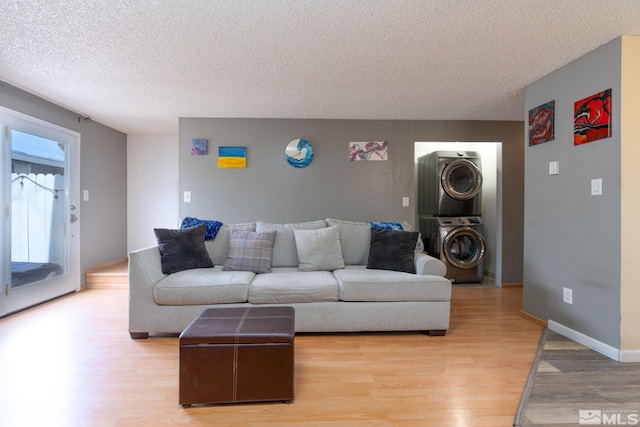 living room featuring a textured ceiling, light hardwood / wood-style floors, and stacked washer / drying machine