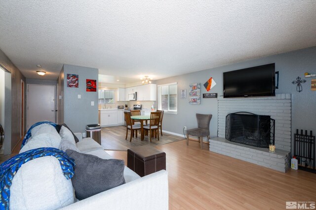 living room featuring a fireplace, light hardwood / wood-style flooring, and a textured ceiling